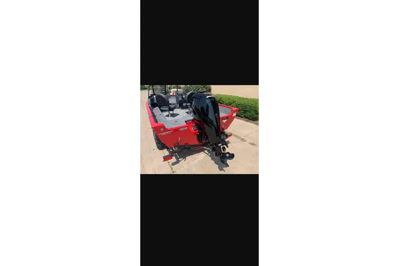 Slide: The Image of 2026 Tracker Pro Guide V-16 WT boat, red exterior, parked on pavement. - 15