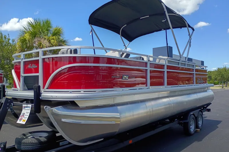 The Image of 2026 Sun Tracker Sportfish 24 XP3 pontoon boat with red exterior and canopy on trailer. - 0