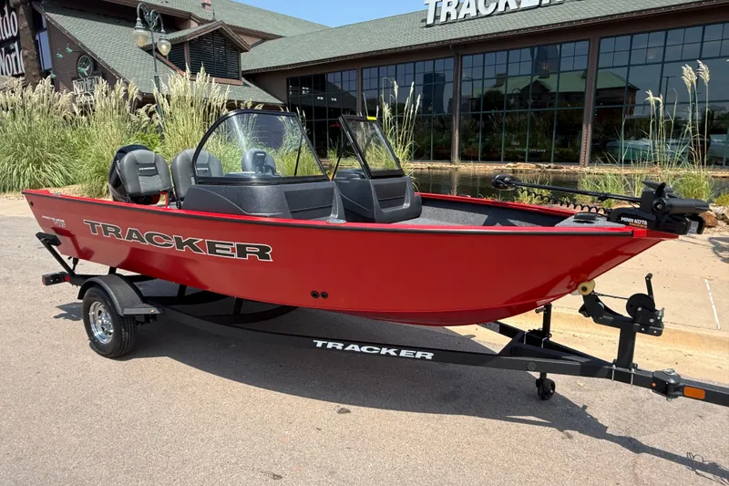 Slide: The Image of 2026 Tracker Pro Guide V-16 WT boat in vibrant red on a trailer outside a showroom. - 18