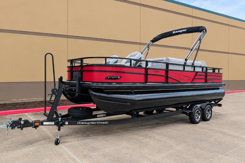Slide: The Image of 2026 Ranger 220F pontoon boat on trailer, red and black design, parked outdoors. - 1