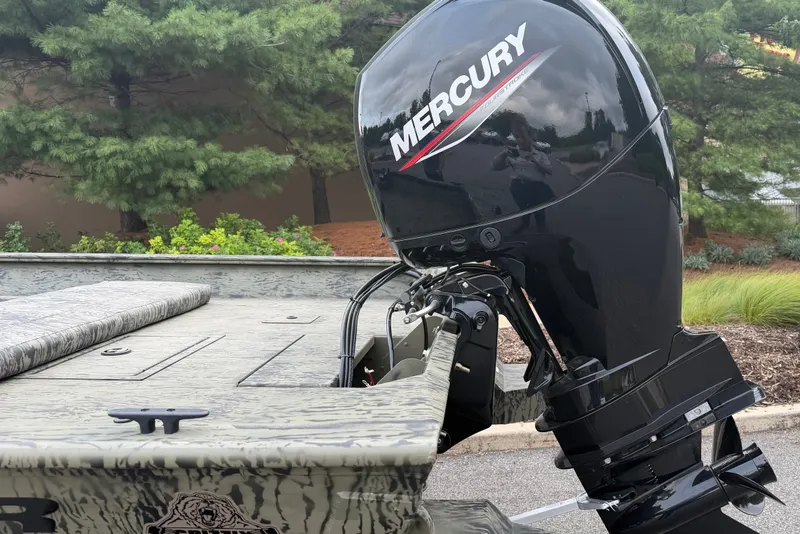 Slide: The Image of 2026 Tracker Grizzly 2072 CC boat with Mercury outboard motor, parked near lush greenery. - 8