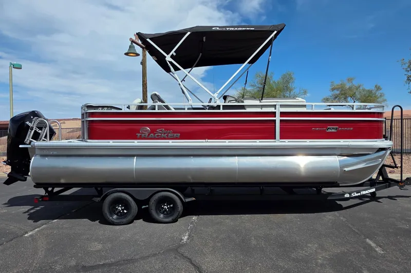 The Image of 2026 Sun Tracker Fishin' Barge 22 XP3 pontoon boat on trailer, red and silver design. - 0