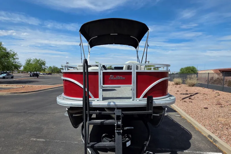 Slide: The Image of 2026 Sun Tracker Fishin' Barge 22 XP3 pontoon boat on trailer, parked outdoors. - 2