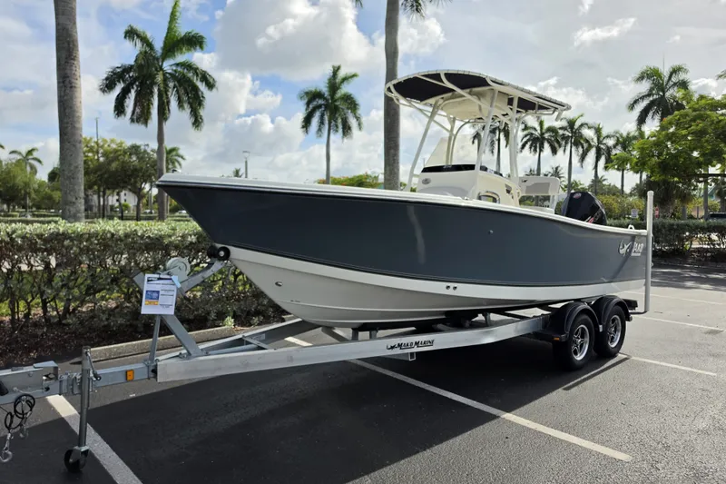 Slide: The Image of 2024 Mako 214 Center Console boat on trailer, parked with palm trees in the background. - 2