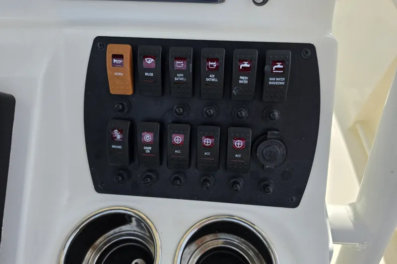 Slide: The Image of Control panel of 2024 Mako 214 Center Console boat with labeled switches and cup holders. - 13