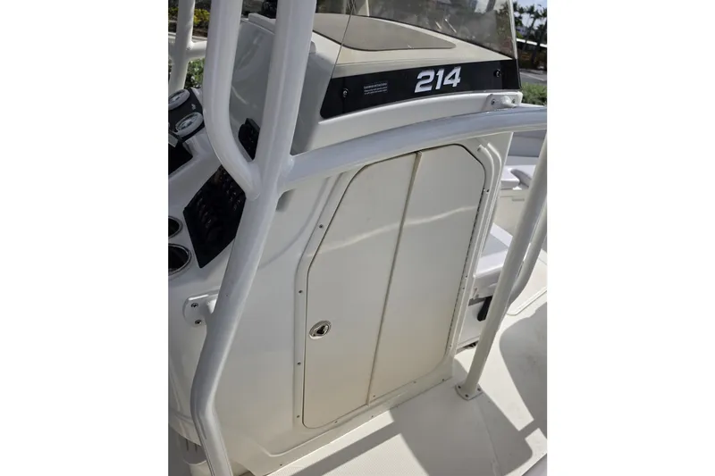 Slide: The Image of 2024 Mako 214 Center Console boat interior, featuring control panel and storage compartment. - 17