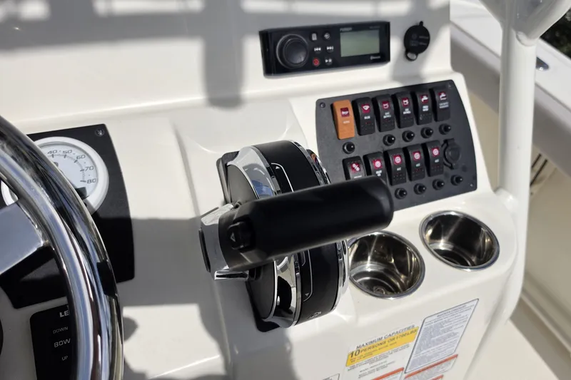 Slide: The Image of 2024 Mako 214 Center Console dashboard with controls, gauges, and cup holders. - 10