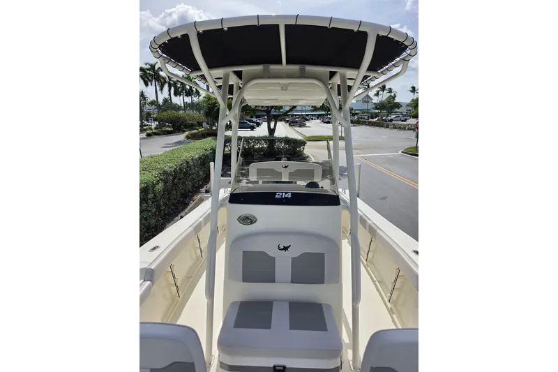 Slide: The Image of 2024 Mako 214 Center Console boat with T-top, parked outdoors on a sunny day. - 11