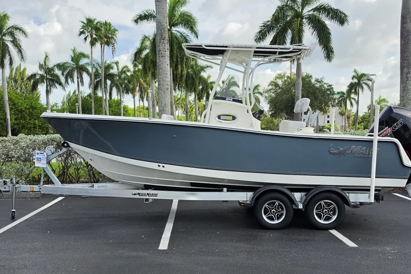 The Image of 2024 Mako 214 Center Console boat on trailer, parked with palm trees in the background. - 0