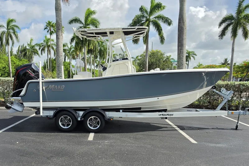 Slide: The Image of 2024 Mako 214 Center Console boat on trailer, parked with palm trees in the background. - 1