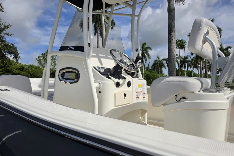Slide: The Image of 2024 Mako 214 Center Console boat interior with steering wheel and seating, under a sunny sky. - 6