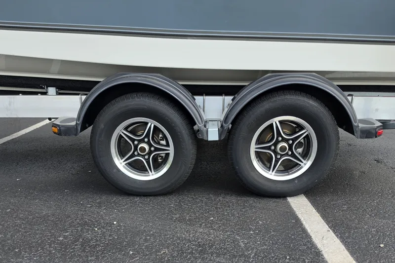 Slide: The Image of Trailer wheels of a 2024 Mako 214 Center Console boat on asphalt. - 21