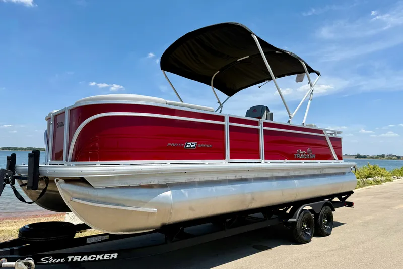 Slide: The Image of 2026 Sun Tracker Party Barge 22 RF DLX pontoon boat on trailer by a lake. - 14