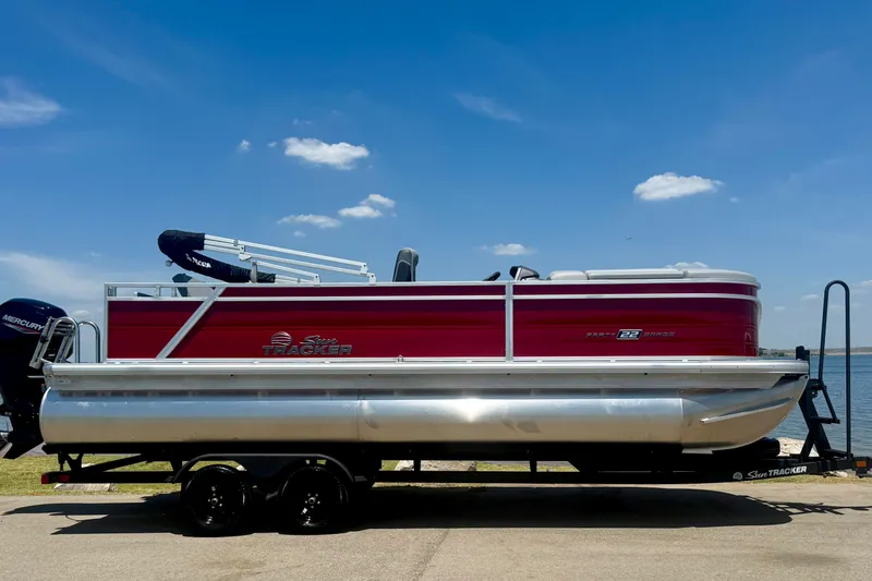 Slide: The Image of 2026 Sun Tracker Party Barge 22 RF DLX pontoon boat on trailer by a lake. - 2