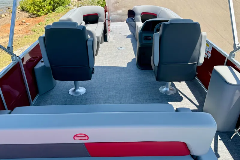 Slide: The Image of 2026 Sun Tracker Party Barge 22 RF DLX interior with seating and helm, near water. - 9