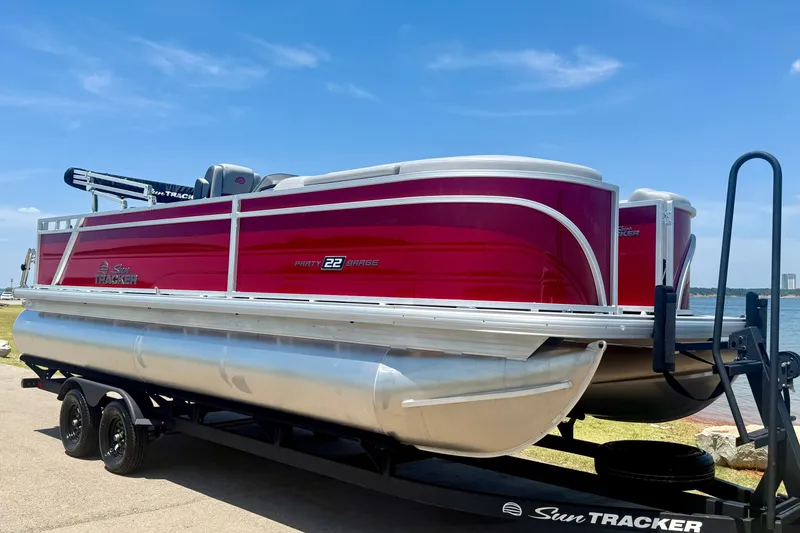 Slide: The Image of 2026 Sun Tracker Party Barge 22 RF DLX pontoon boat on trailer by the water. - 1