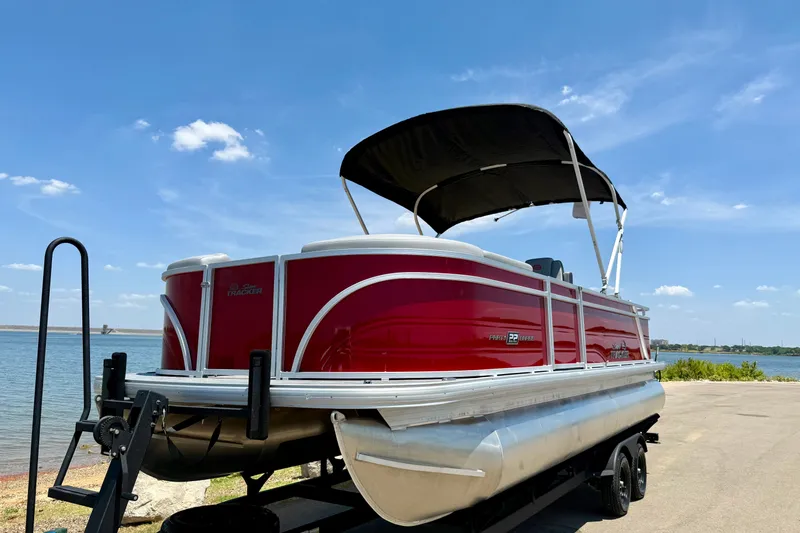 Slide: The Image of 2026 Sun Tracker Party Barge 22 RF DLX pontoon boat on trailer by a lake. - 16
