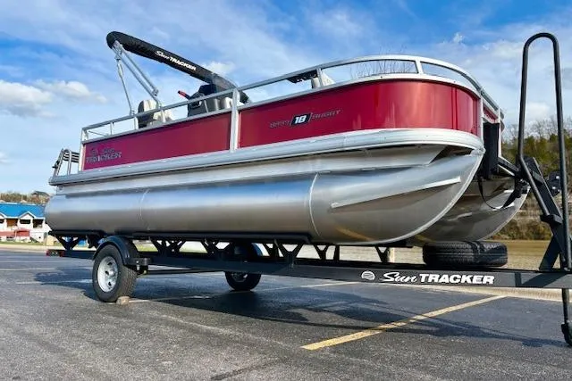 Slide: The Image of 2026 Sun Tracker Bass Buggy 18 DLX pontoon boat on trailer, parked outdoors. - 13