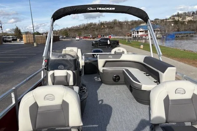 Slide: The Image of 2026 Sun Tracker Bass Buggy 18 DLX pontoon boat with spacious seating, parked near a scenic lake. - 14