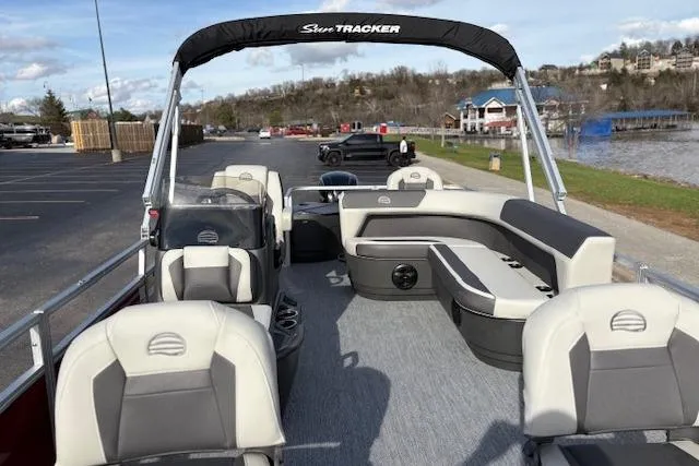 Slide: The Image of 2026 Sun Tracker Bass Buggy 18 DLX pontoon boat with spacious seating, docked near a scenic lake. - 15