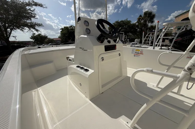 Slide: The Image of 2026 Mako Pro Skiff 19 CC boat interior with steering console under a sunny sky. - 1