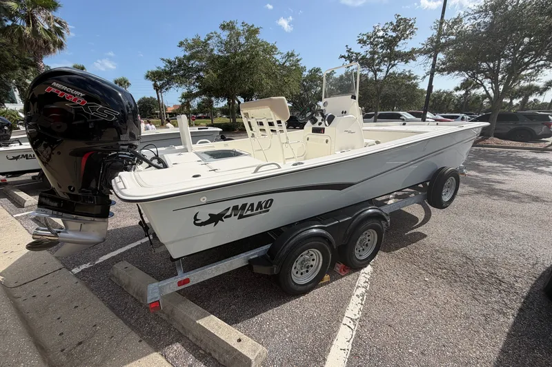 The Image of 2026 Mako Pro Skiff 19 CC boat on trailer, parked outdoors with trees in background. - 0