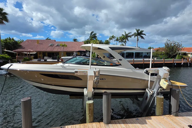 Slide: The Image of 2015 Sea Ray SLX 350 boat docked by waterfront homes under a cloudy sky. - 1