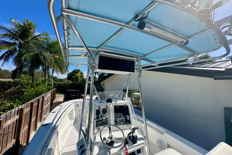 Slide: The Image of 2001 Contender 23 Open boat with blue canopy, steering console, and tropical background. - 28