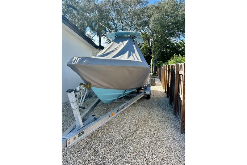 Slide: The Image of Covered 2001 Contender 23 Open boat on trailer, parked on gravel beside a house. - 9