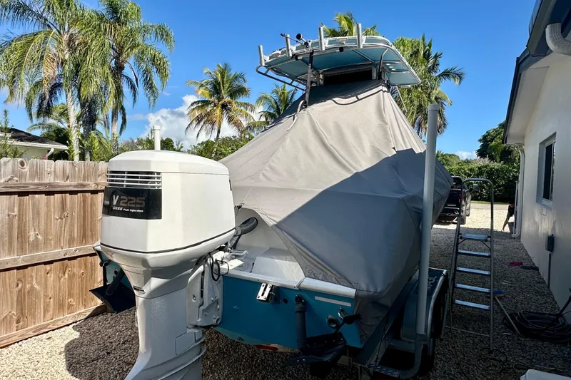Slide: The Image of 2001 Contender 23 Open boat with cover, parked outdoors near palm trees. - 11