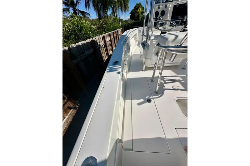 Slide: The Image of 2001 Contender 23 Open boat deck with steering console and seating, surrounded by lush greenery. - 41