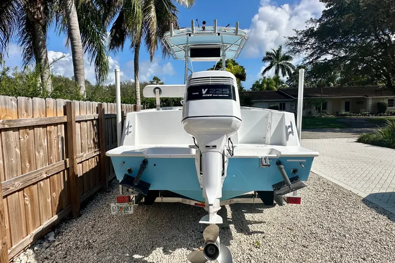 Slide: The Image of 2001 Contender 23 Open boat with V225 engine, parked on gravel, surrounded by palm trees. - 3