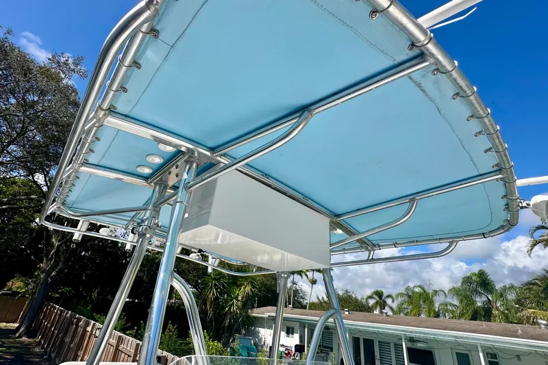 Slide: The Image of 2001 Contender 23 Open boat T-top with blue canvas under clear sky. - 25