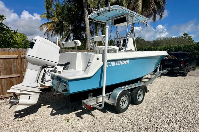 Slide: The Image of 2001 Contender 23 Open boat on trailer, parked outdoors with palm trees in background. - 2