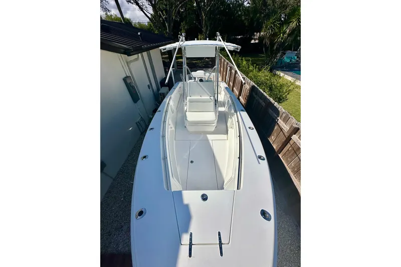 Slide: The Image of 2001 Contender 23 Open boat, white deck, parked beside a house and wooden fence. - 14