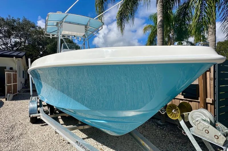 Slide: The Image of 2001 Contender 23 Open boat on trailer, blue hull, palm trees in background. - 7