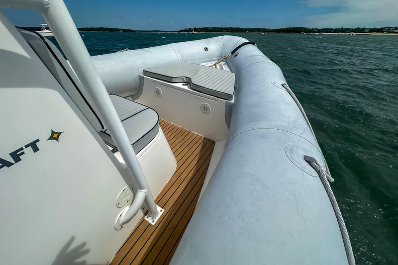 Slide: The Image of 2019 Ribcraft 6.8 boat on water, featuring cushioned seating and wooden deck. - 14