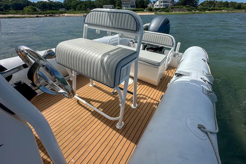 Slide: The Image of 2019 Ribcraft 6.8 boat with teak deck, cushioned seating, and steering wheel on calm water. - 16