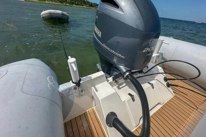 Slide: The Image of Ribcraft 6.8 boat with Yamaha 200 engine, towing a small inflatable on calm water. - 21
