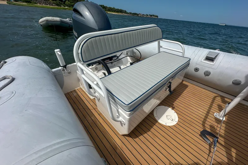 Slide: The Image of 2019 Ribcraft 6.8 boat with cushioned seating, wooden deck, and Yamaha engine on water. - 19