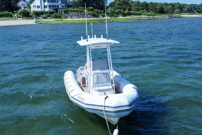 Slide: The Image of 2019 Ribcraft 6.8 boat anchored near a scenic shoreline. - 2