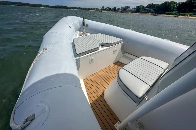 Slide: The Image of 2019 Ribcraft 6.8 boat interior with cushioned seating and teak flooring on the water. - 10