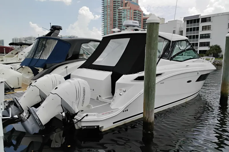 The Image of 2023 Sea Ray Sundancer 320 Outboard docked at marina, featuring twin Mercury engines. - 5