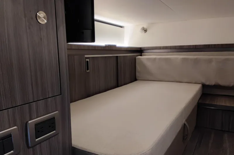 Slide: The Image of 2023 Sea Ray Sundancer 320 Outboard cabin interior with modern wood finish and cozy bed. - 30