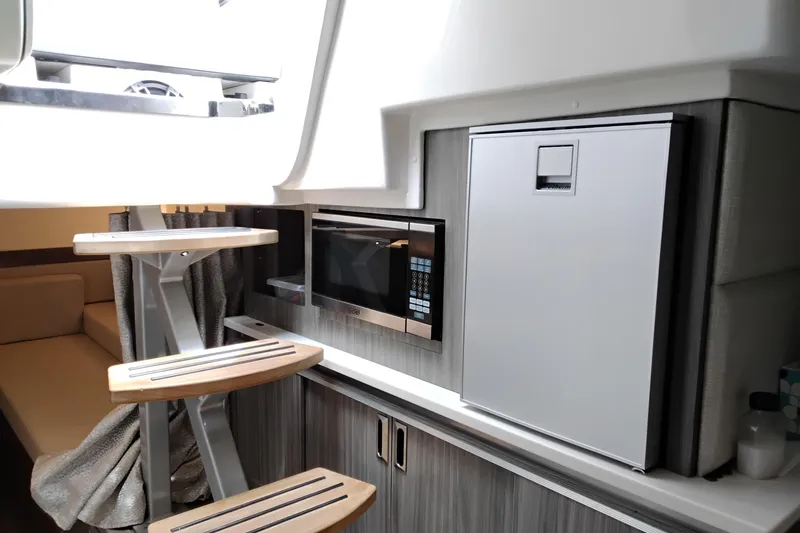 Slide: The Image of 2023 Sea Ray Sundancer 320 Outboard interior with microwave and compact fridge. - 24