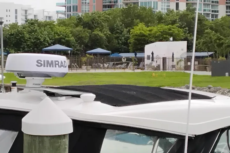 Slide: The Image of 2023 Sea Ray Sundancer 320 Outboard with Simrad radar, docked near a poolside area. - 6
