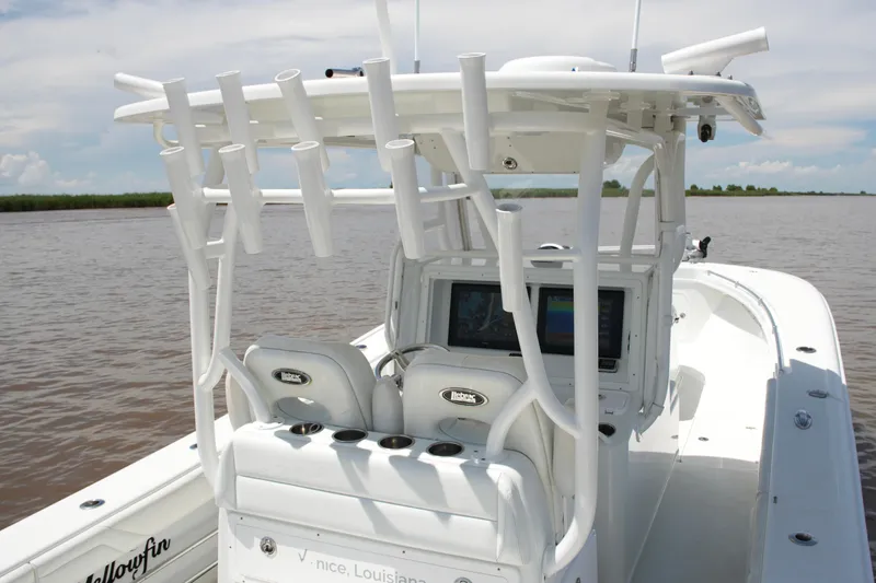 Slide: The Image of 2016 Yellowfin 32 Offshore boat with rod holders and navigation screens on a calm waterway. - 33