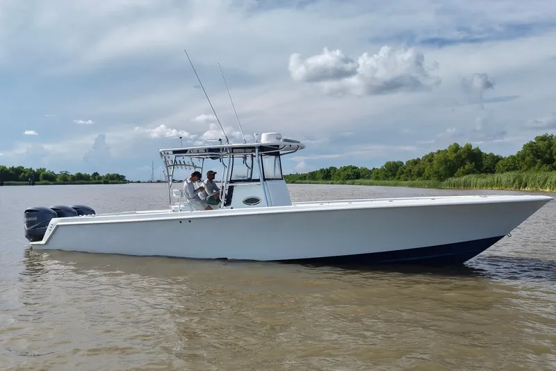 Slide: The Image of 2013 Contender 39 ST boat on calm water with clear skies and lush greenery. - 12