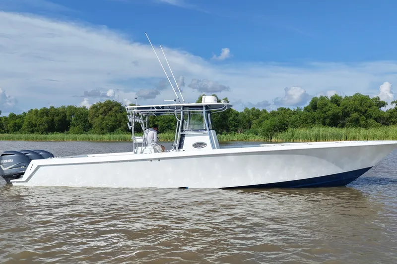 Slide: The Image of 2013 Contender 39 ST boat on water, clear sky, lush green background. - 11