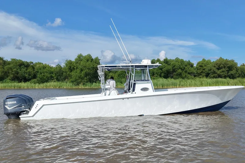 Slide: The Image of 2013 Contender 39 ST boat on water with Yamaha engine, clear sky, and lush greenery. - 1